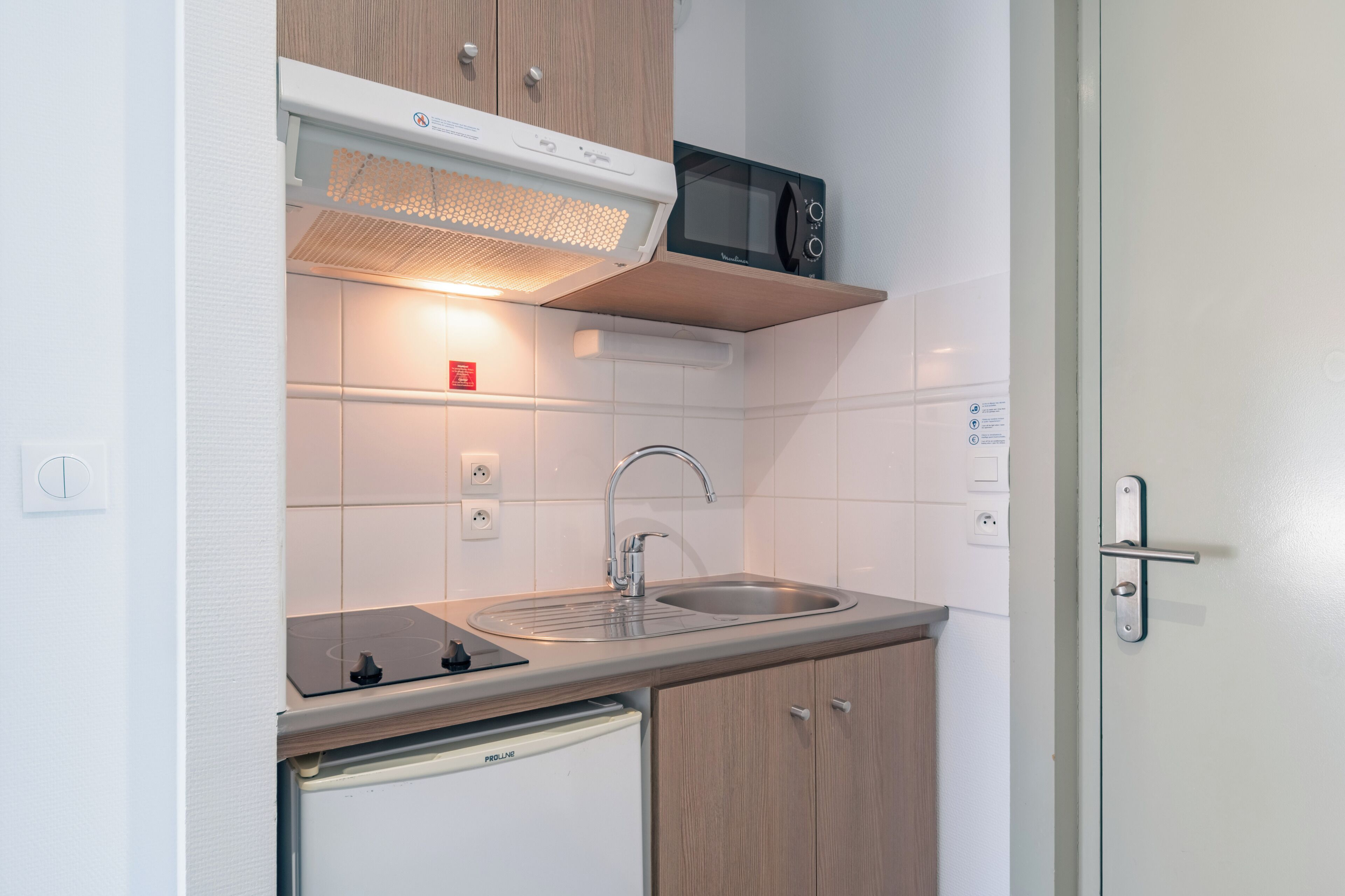 A compact kitchen with a microwave, sink, and built-in oven.