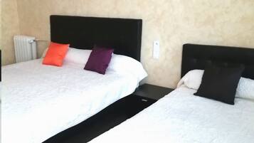Ein Hotelzimmer mit zwei Betten, jeweils mit schwarzem Kopfteil und weißer Bettwäsche. Es gibt zwei Nachttische, einen an jedem Bett. Die Wände sind beige, und es sind zwei kleine Wandleuchten angebracht.