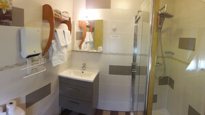 A modern bathroom with a glass-enclosed shower, a sink, and a vanity with drawers. - Hôtel Restaurant Métropole (Mirande)