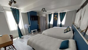 A hotel room with two beds, a desk, a chair, a fan, and a TV. - Hôtel Restaurant Métropole (Mirande)