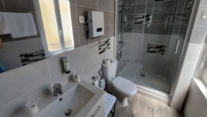 A modern bathroom with a glass-enclosed shower, a white sink, and a toilet. - Hôtel Restaurant Métropole (Mirande)