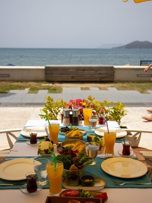 A table set for a meal with a view of the sea and mountains in the background.