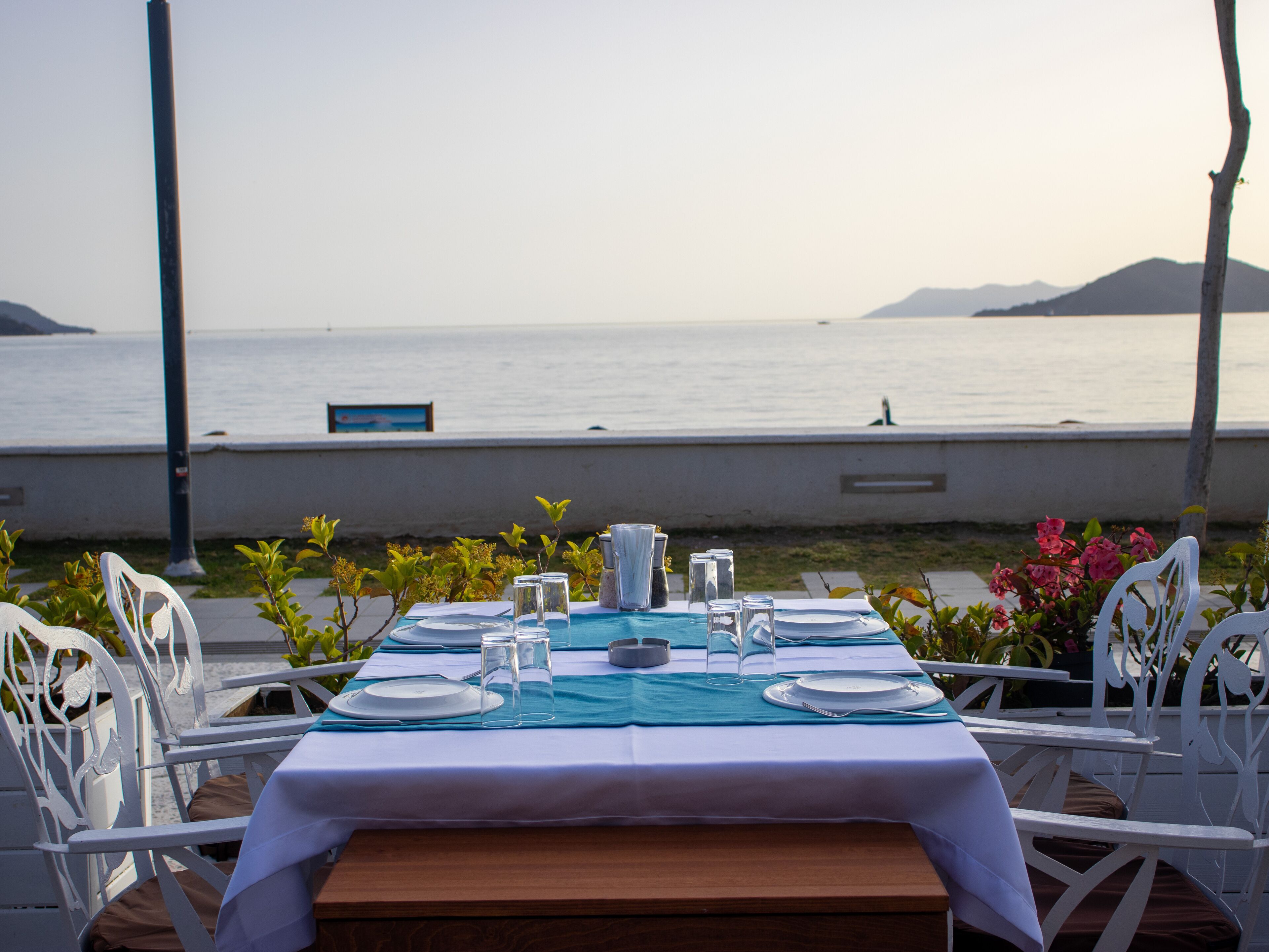 A table set for dining with a view of the sea and mountains.