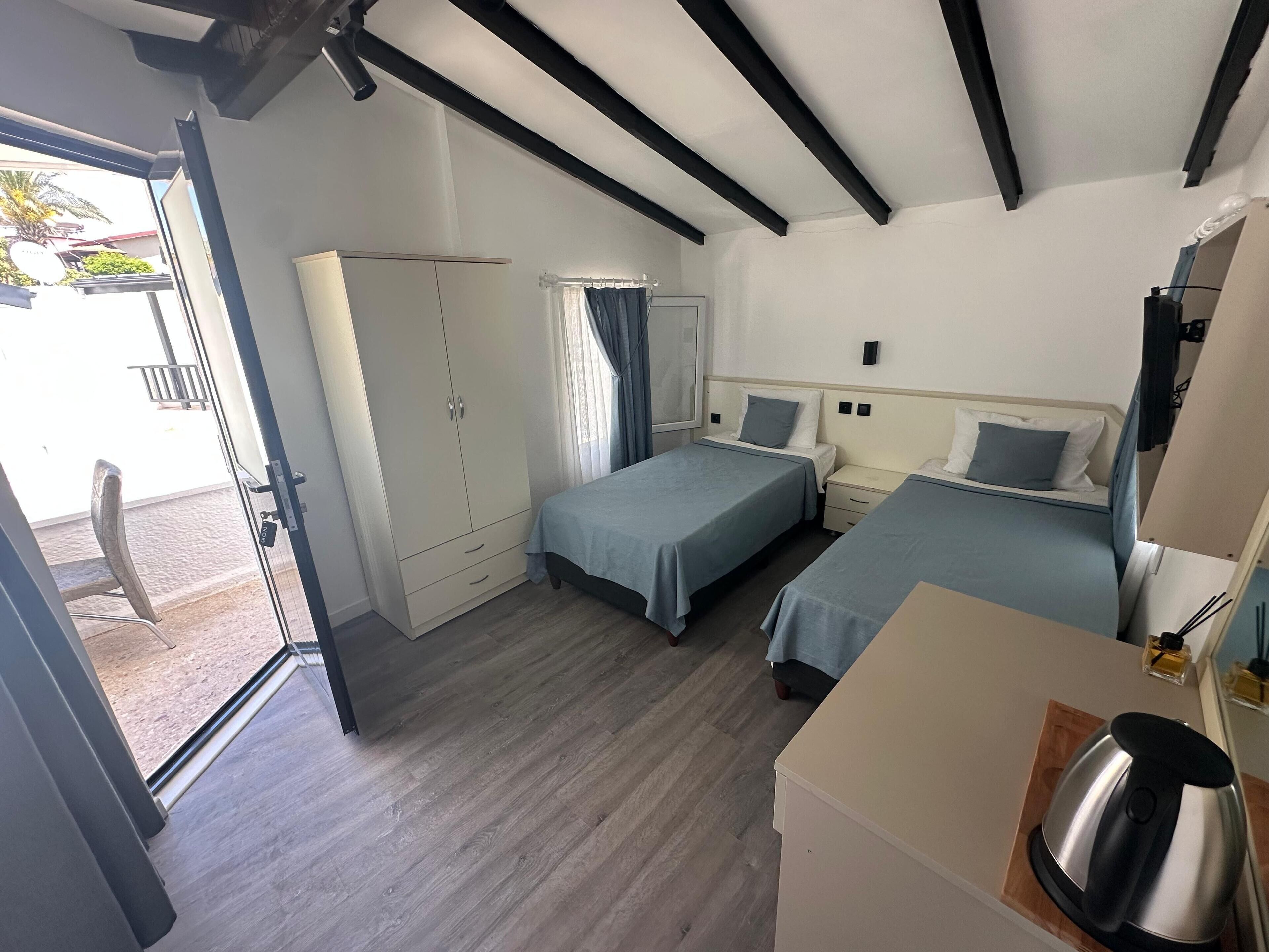 Una habitación con dos camas, un armario, un escritorio y una kitchenette.
