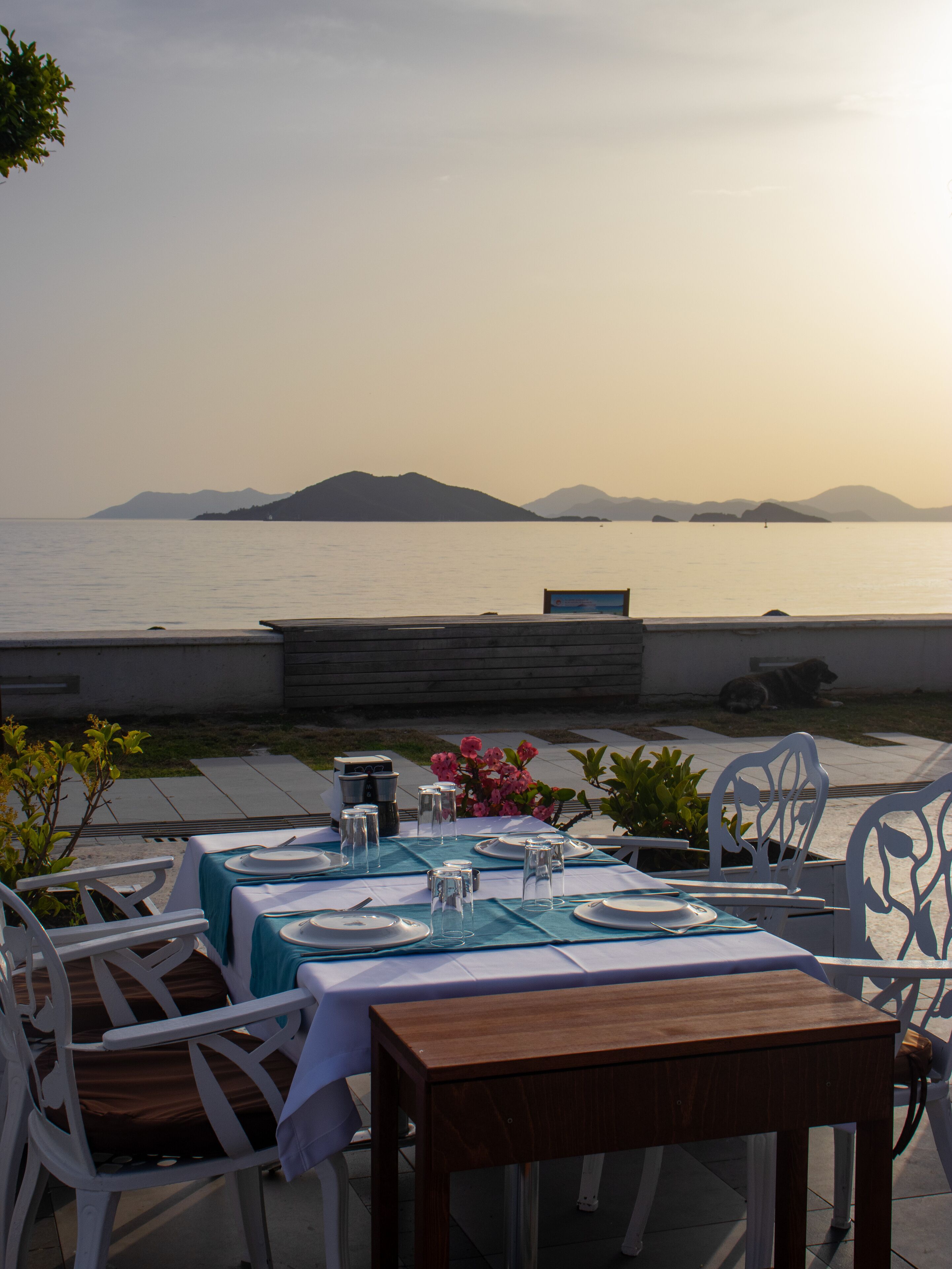 An outdoor dining area with a view of the sea and mountains.