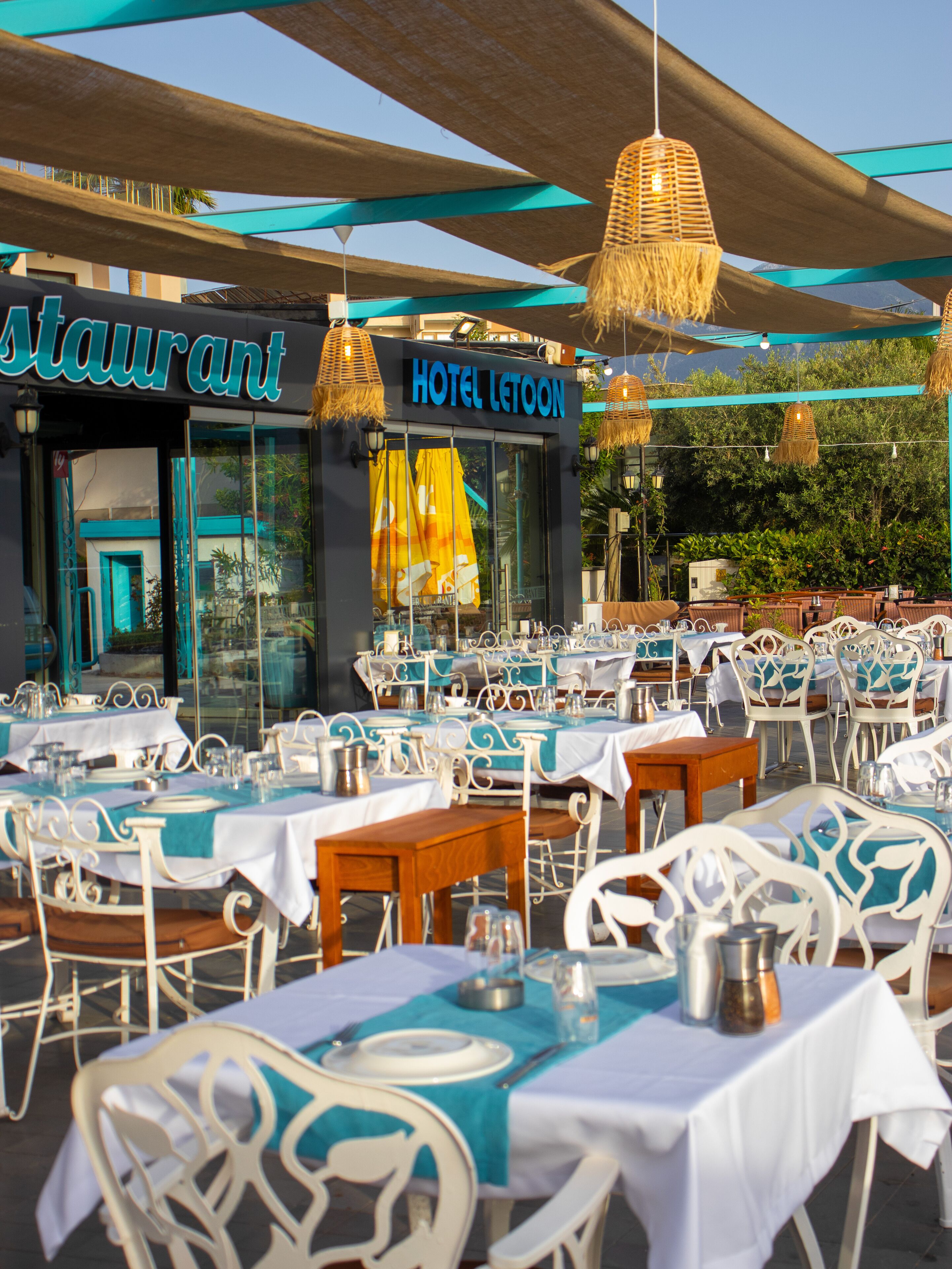 An outdoor dining area with tables and chairs, a restaurant sign, and a hotel sign.