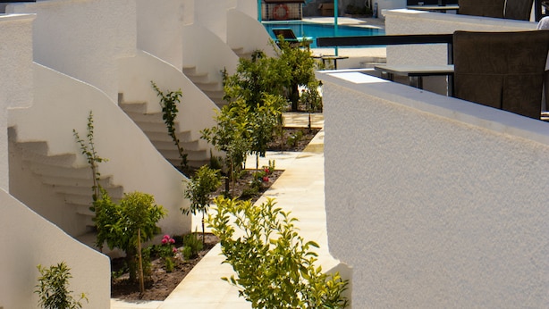 A resort with multiple balconies, a pool, and a view of the sea.