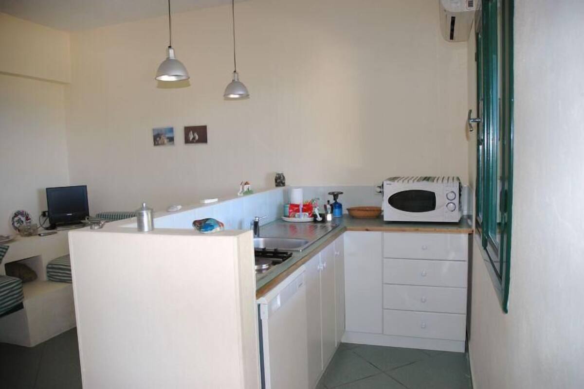 A compact kitchen with a microwave, sink, and two pendant lights.