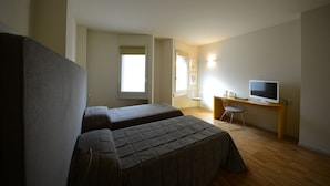 A room with two beds, a desk with a computer, and a TV.