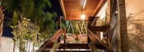 A staircase with two wicker chairs under a wooden canopy, surrounded by greenery. - Estate Spa (Rehovot)