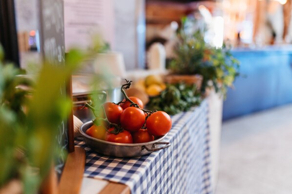 A table with a metal bowl of tomatoes and a checkered tablecloth.