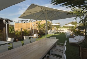 Enjoy dining or socializing in a shaded patio area with a table, chairs, and comfortable sofa.