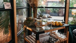 Une table en bois rustique, ornée d’un vase en verre, de carafes d’eau et d’un saladier rempli de citrons.