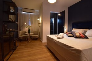 Relax in a stylish room with a large bed, armchairs, and a vase of flowers.