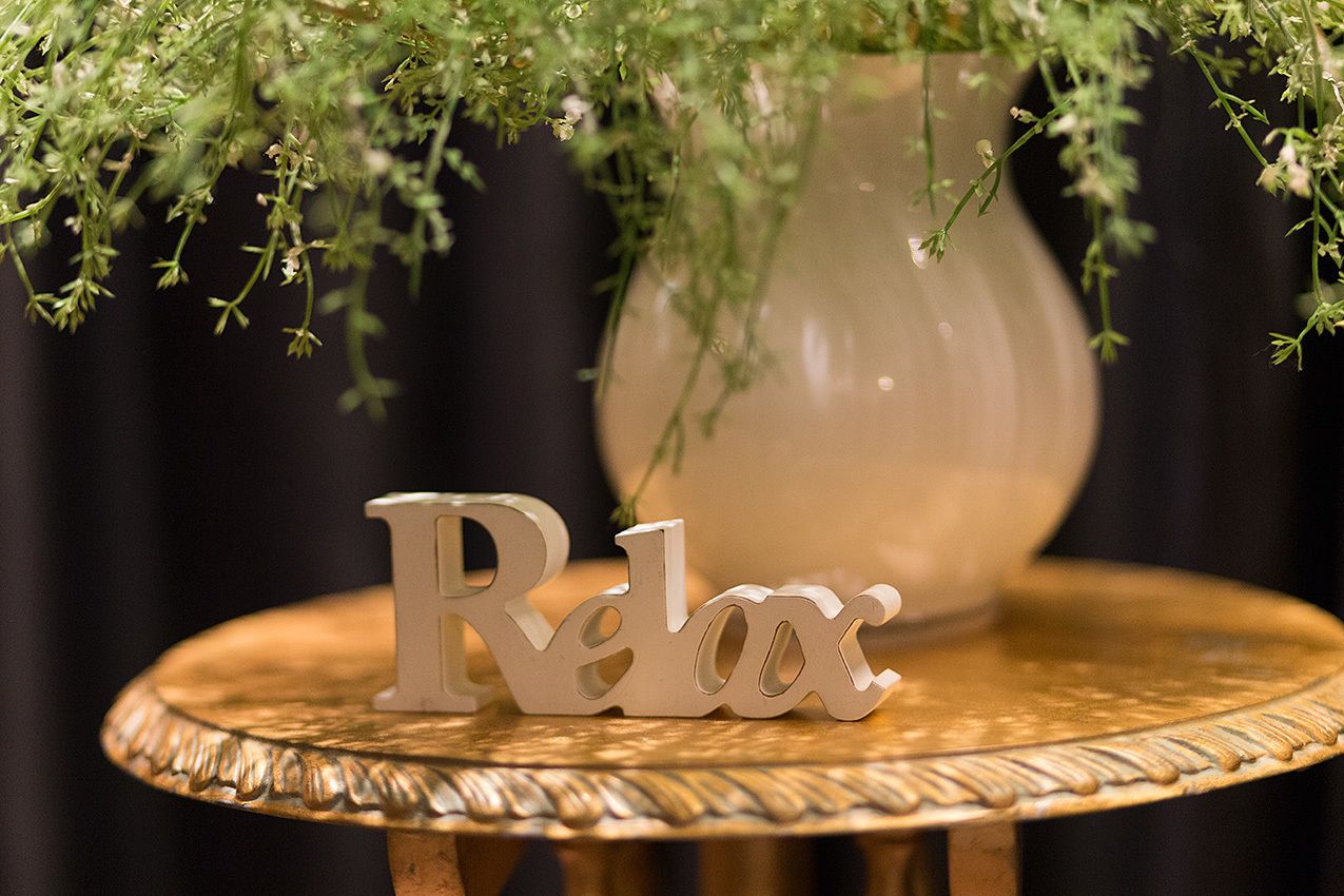 Una mesa con un adorno que dice 'Relax' y un florero con follaje verde.