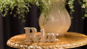 Una mesa con un adorno que dice 'Relax' y un florero con follaje verde.