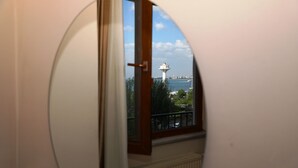 Espejo circular que refleja un faro, una ventana y un radiador.