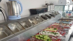 Un bufé con diversos alimentos, como verduras cortadas, carnes y productos de pastelería.