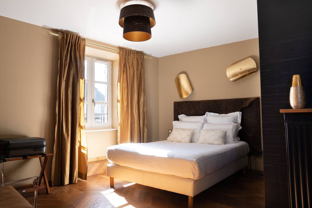 A neatly arranged bedroom with a bed, curtains, a bedside table, and a lamp.
