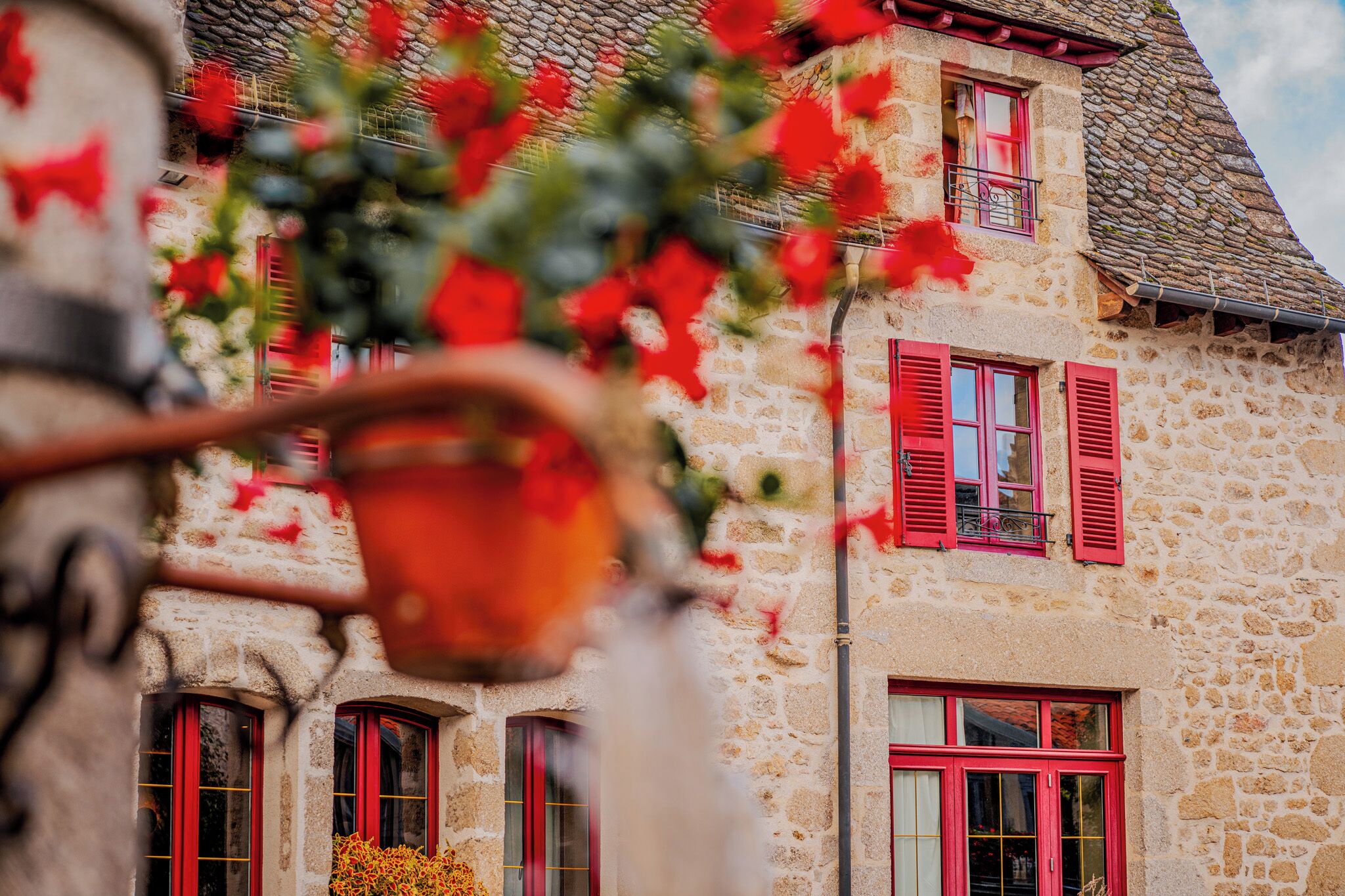 Un bâtiment en pierre avec des volets rouges et un balcon.