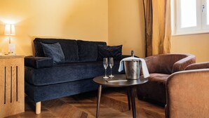 A cozy room with a dark blue sofa, a small round table with two glasses and a bucket, and a wooden cabinet.