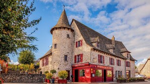 A stone building with a tower, red shutters, and a sign reading "Auberge de la Tour."