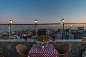 A terrace with a table and chairs, potted plants, and lanterns.