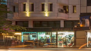 Un edificio de varios pisos con balcones y una tienda en la planta baja.