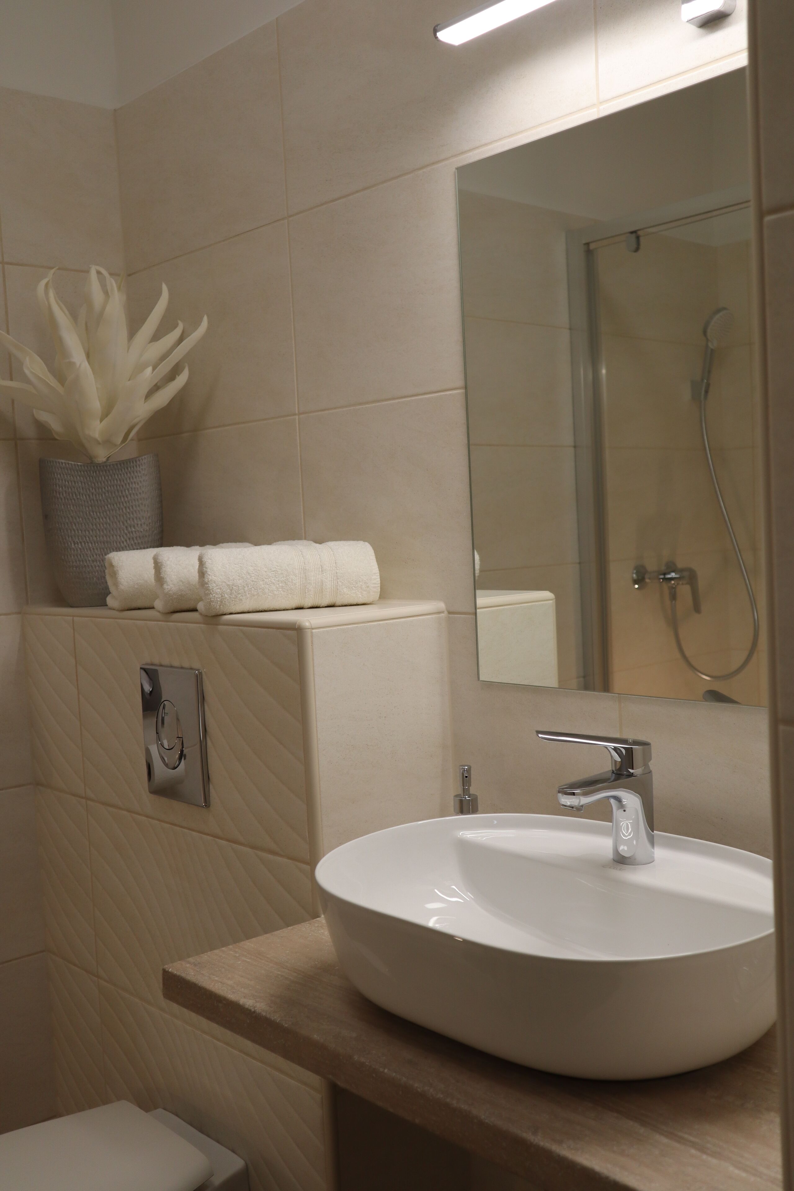 Een moderne badkamer met een rond wastafel, een spiegel, een toilet en een douche.