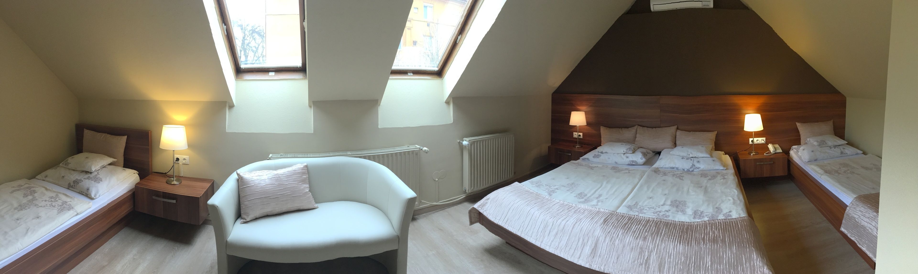 A bedroom with two single beds, a chair, and a small table with a lamp.