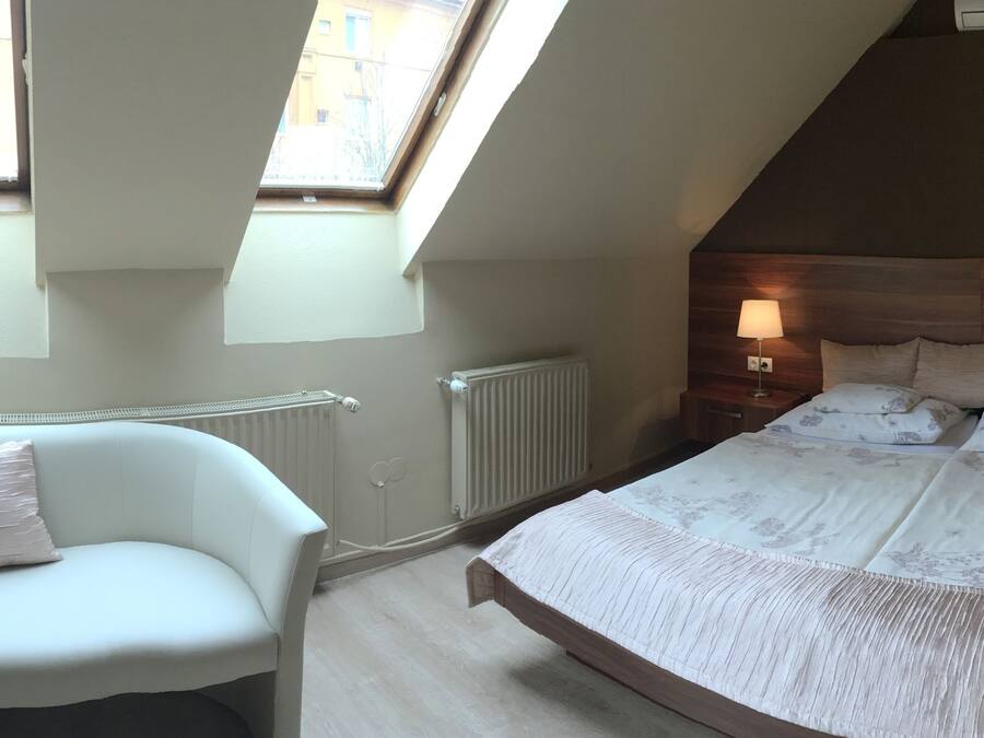 A bedroom with two single beds, a chair, and a small table with a lamp.
