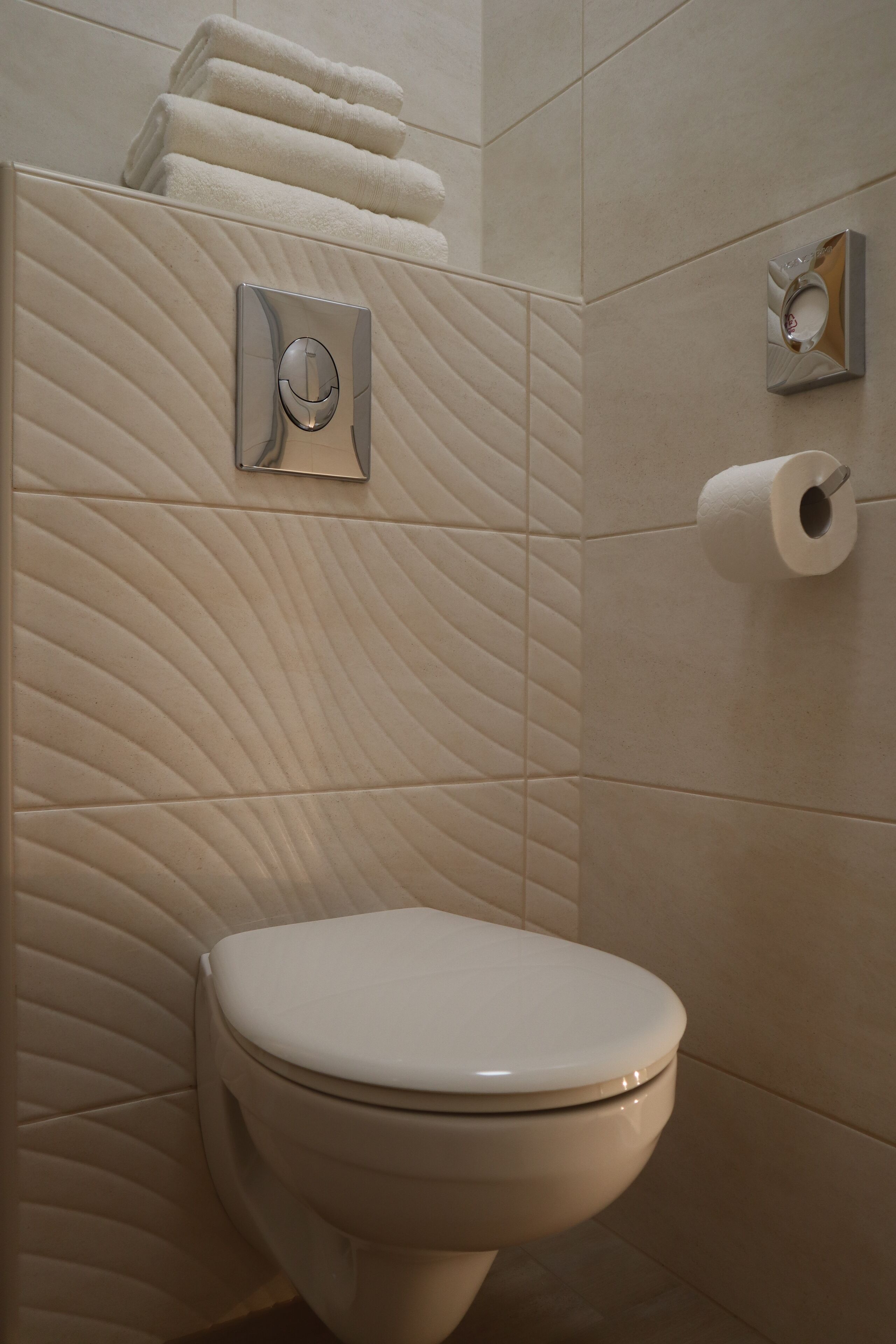 Une salle de bain moderne équipée de toilettes, d'un distributeur de serviettes et d'un porte-rouleau de papier toilette.