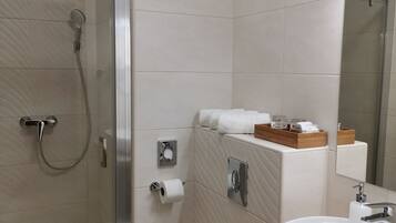 A modern bathroom with a glass-enclosed shower, a toilet, and a sink with a mirror.