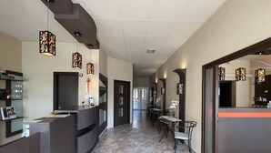 Un espace d’accueil d’hôtel comprenant un comptoir de réception, des chaises et des appliques murales décoratives.
