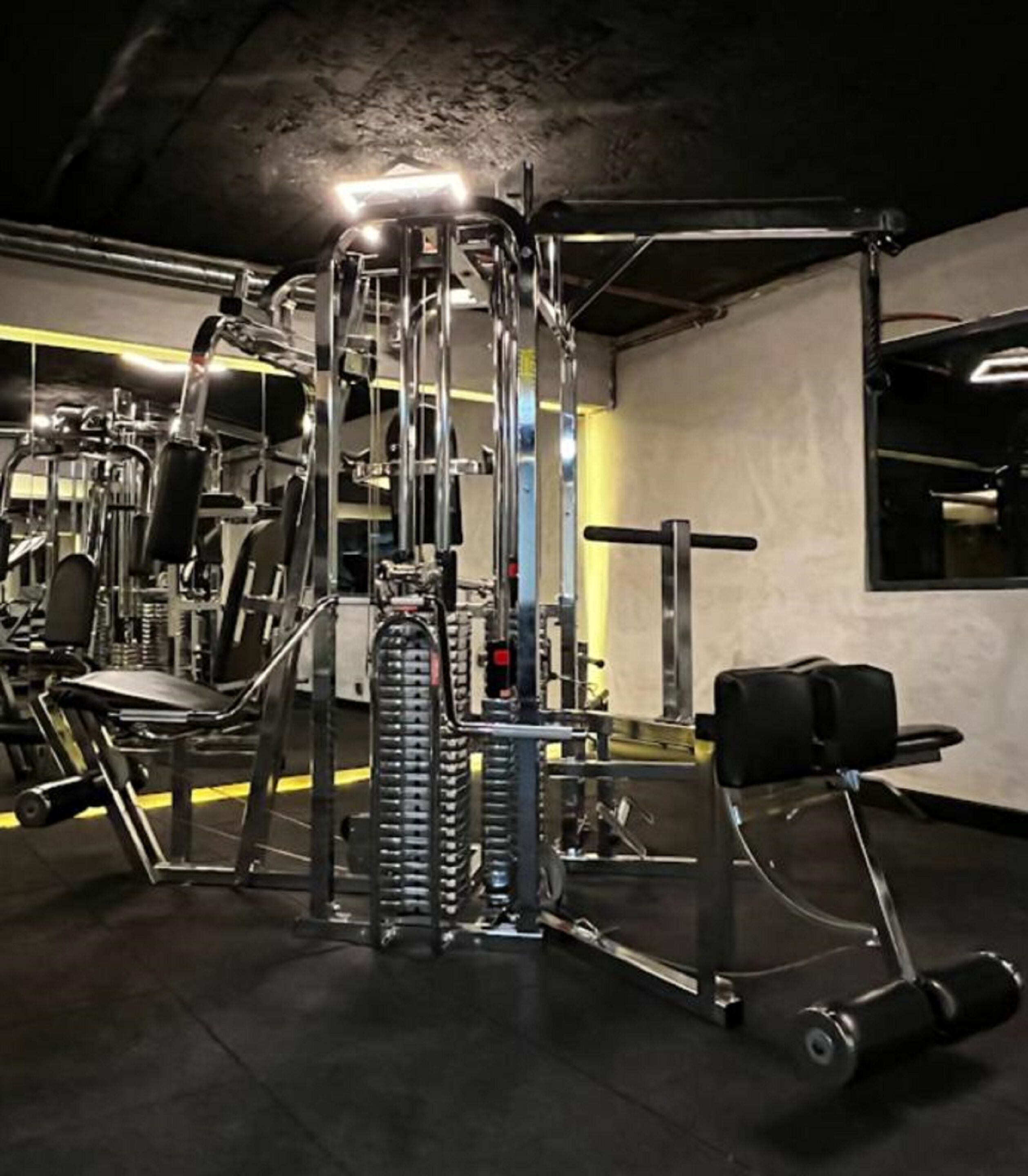 A gym with various exercise machines, including a cable machine and weight benches.