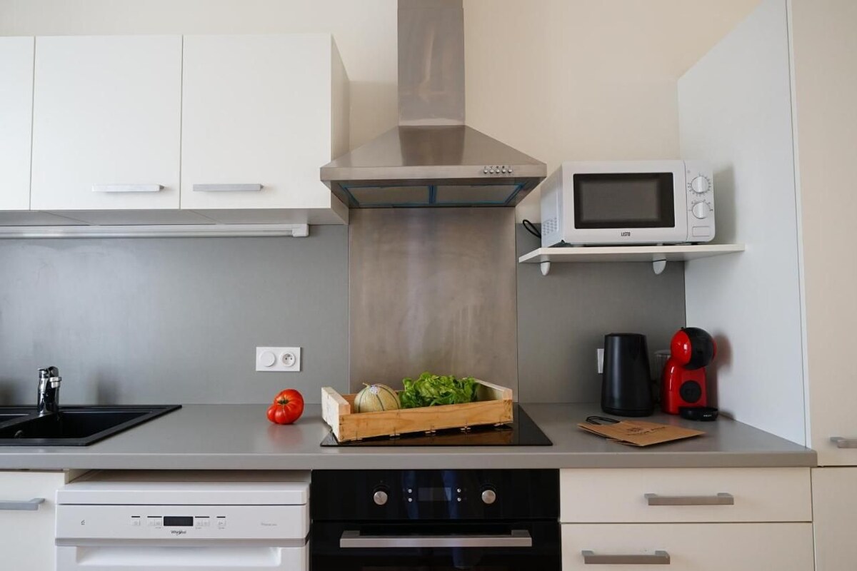 A modern kitchen with white cabinets, a stainless steel range hood, a microwave, and a coffee maker on the countertop.