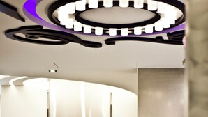An elevator with a metallic finish, a luggage trolley, and a modern ceiling design with circular patterns. - Saual Keh Hotel (Taipei)