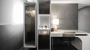Een kleine hotelkamer met kitchenette, bureau en stoel.
