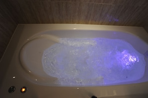 Een badkuip met een whirlpoolfunctie en twee verlichte knoppen.