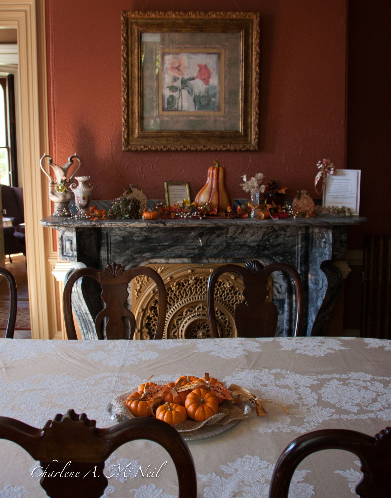 A dining area with a table set for a meal, a fireplace with decorative items, and a framed picture on the wall.