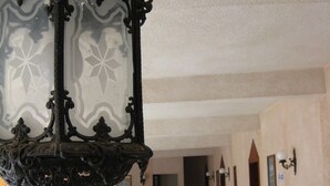 Tilava huone, jossa on ruutukuviollinen lattia, puiset huonekalut ja koristeellinen riippuvalaisin.