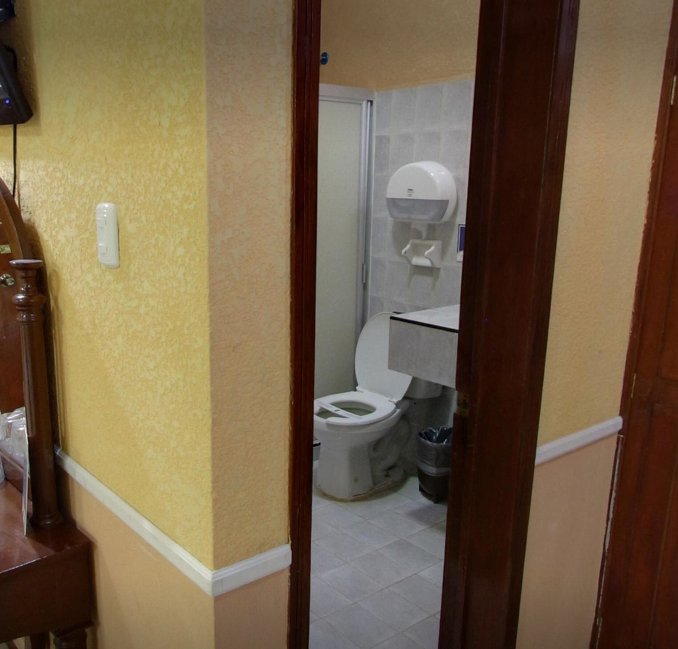 Een badkamer met een toilet, een handdroger en een prullenbak.