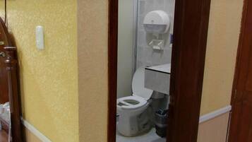 Een badkamer met een toilet, een handdroger en een prullenbak.