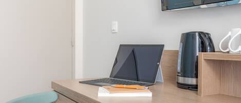 Un espacio de trabajo moderno con una computadora portátil, un cuaderno, un bolígrafo, una cafetera y una silla.