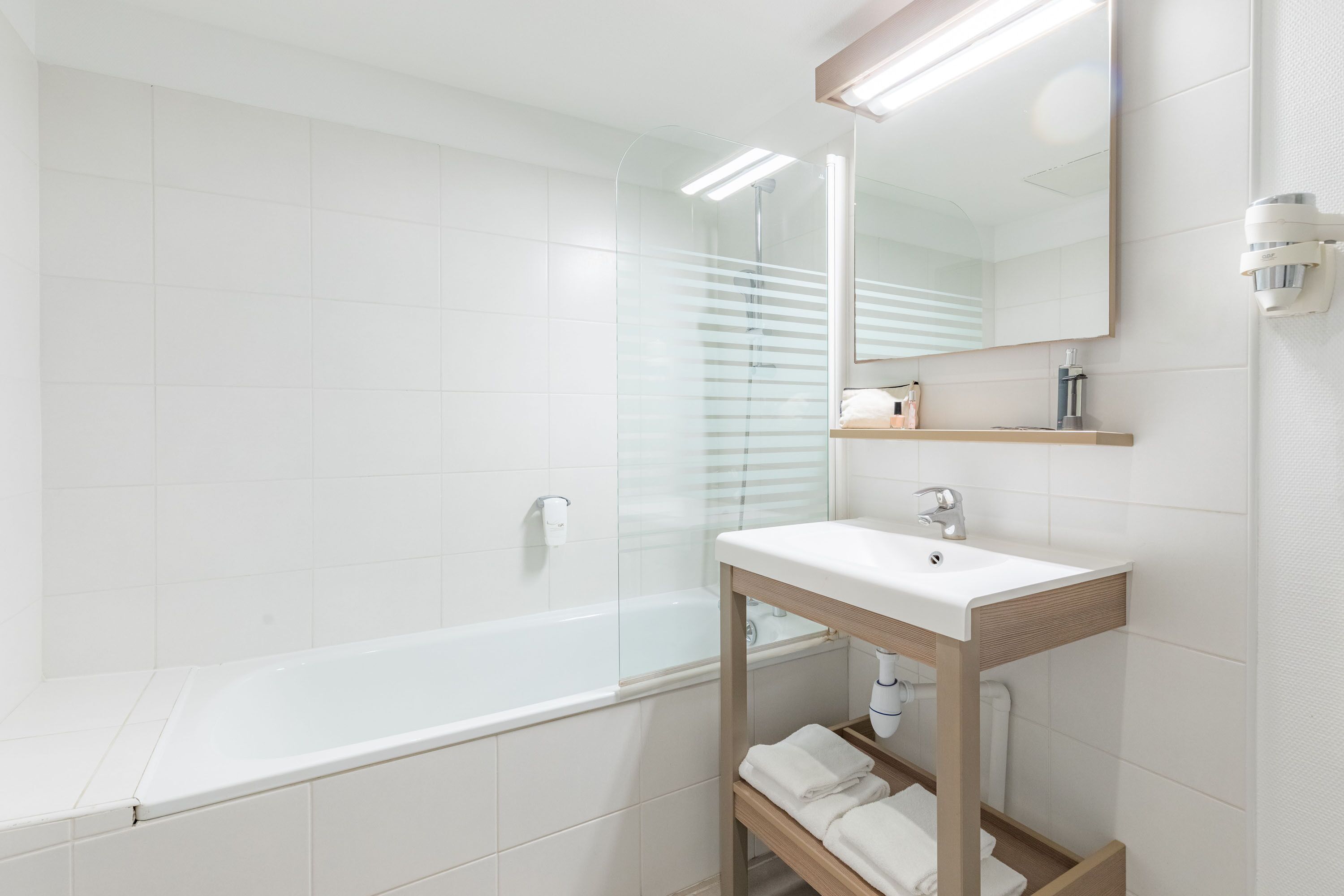 Une salle de bain moderne avec une douche à parois de verre, un lavabo blanc et un miroir au-dessus.
