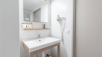 Une salle de bain moderne avec un lavabo blanc, un meuble-lavabo en bois et un miroir au-dessus.