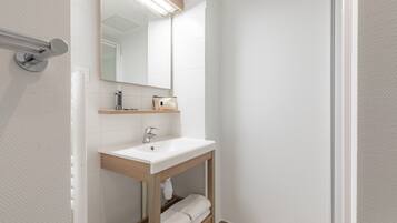 Un baño moderno con lavamanos blanco, espejo y toallero.