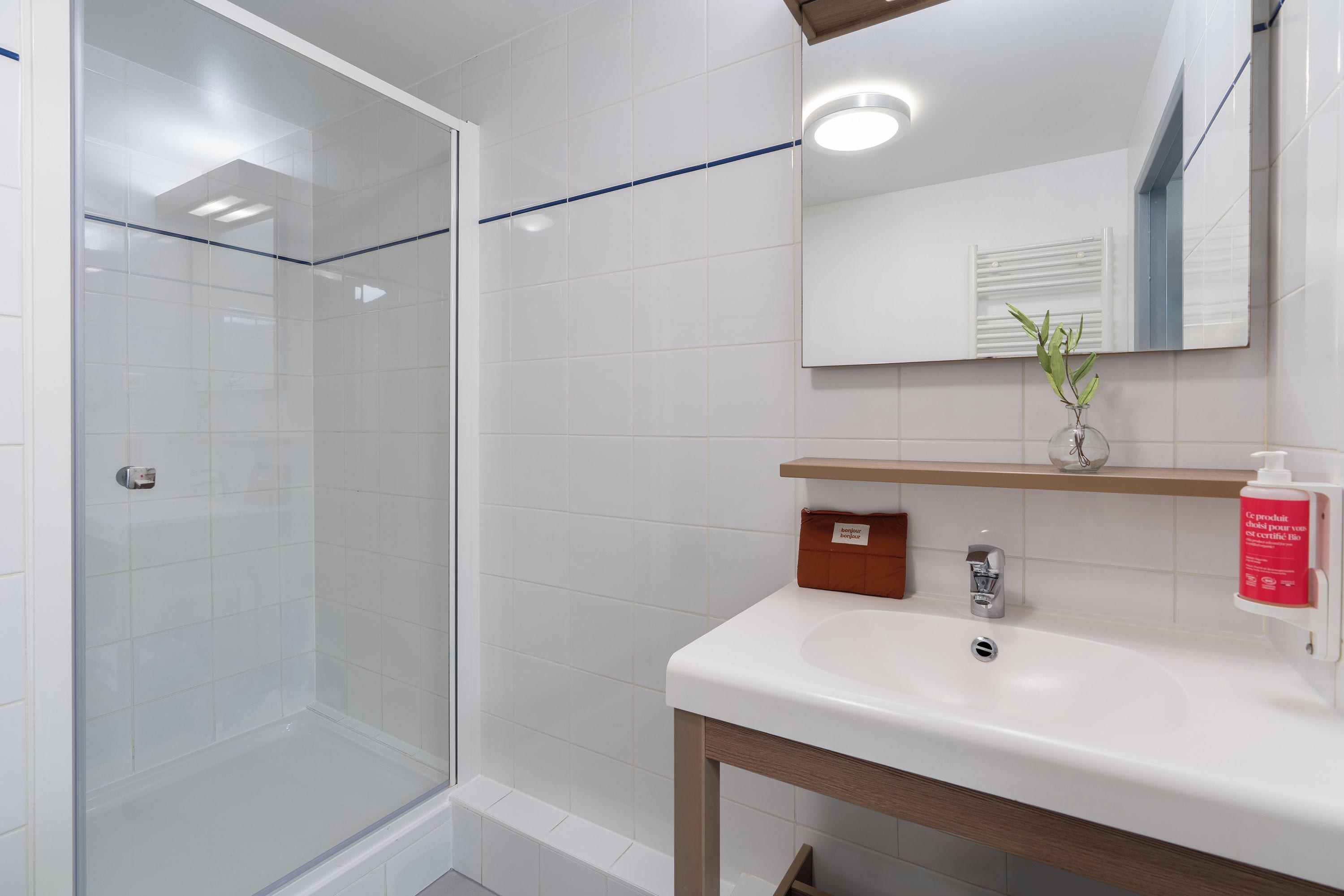 Un baño moderno con cabina de ducha de vidrio, un lavabo blanco y un espejo sobre él.