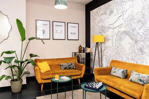 A modern living room with a sofa, a coffee table, and a chessboard. There are framed pictures on the wall, a potted plant, and a floor lamp. - Appart'City Confort Strasbourg Centre (Strasbourg)
