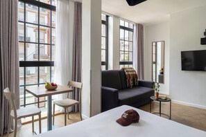 Une chambre d’hôtel moderne équipée d’un lit, d’un canapé, d’une table à manger et d’un téléviseur.